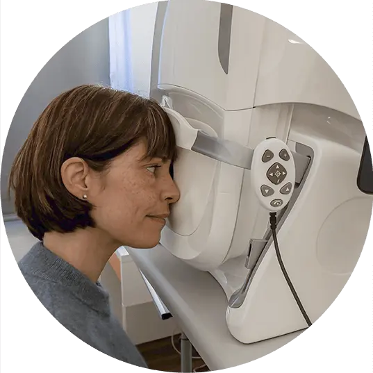 Patientin mit Stirn und Kinn an einem OCT-Netzhautscanner positioniert für die 3D-Raster-OCT-Untersuchung zur Früherkennung von AMD.