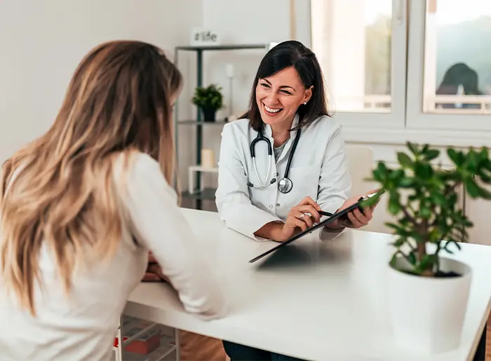 Ärztin im weißen Kittel führt hausärztliche Untersuchung bei Patientin zur Narkose­vorbereitung durch.